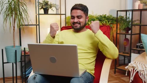 Young Adult Celebrating Success While Using Laptop