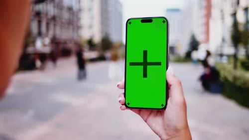 Woman Holding Smartphone with Green Screen in the City