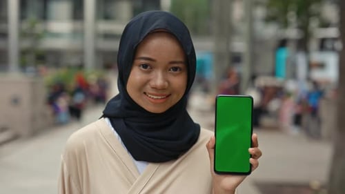 Pretty Islamic Lady Outdoors with a Mobile Phone Showing Chroma Key to the Camera
