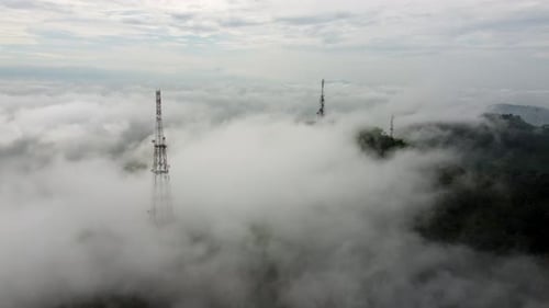 Aerial fly away view the foggy cloud cover telco tower