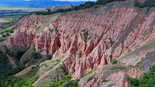 Drone Shot of Eroded Red Cliffs and Green Hills