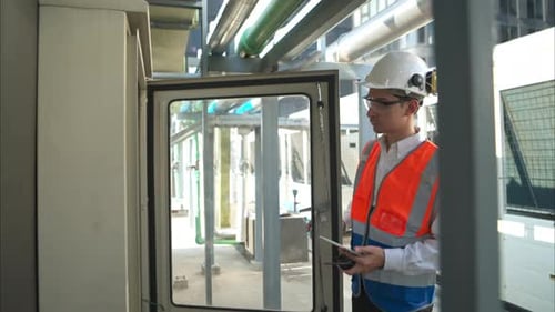 Technician closes electrical box in outdoor industrial environment