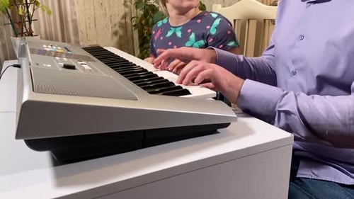 Man and Young Girl Play Keyboard