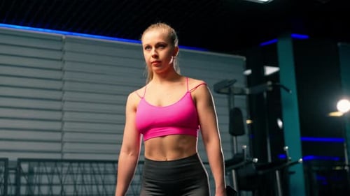 in the Gym Girl with a Ponytail in a Pink Top Does Lunges with Dumbbells in Her Hands