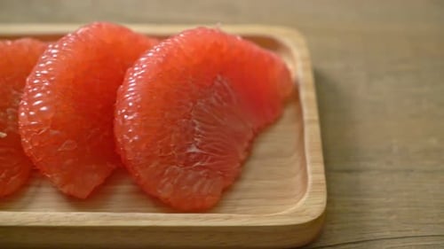 Three Sections of Juicy Pomelo on Wooden Board