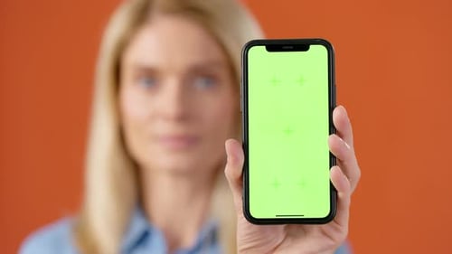 Woman Holding Smartphone with Chroma Key Screen in Studio