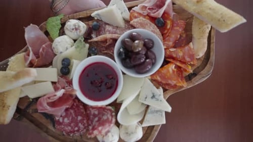 Presenting a delicious charcuterie plate of cured meats, cheese, olives and bread.