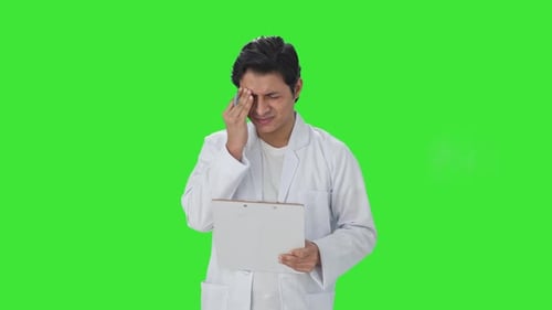 Stressed Indian scientist writing observations on papers Green screen