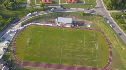 Aerial View of a Football Field on a Stadium Covered with Green Grass in Rural Town Area