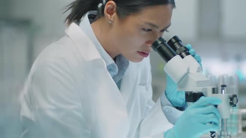 Scientist Using Microscope in Bright Clinical Laboratory