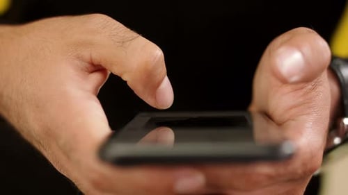 Unrecognizable man using smartphone in studio against yellow background