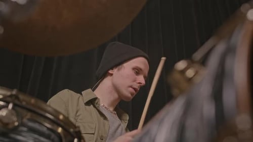 Musician Looking at Camera while Playing Drums