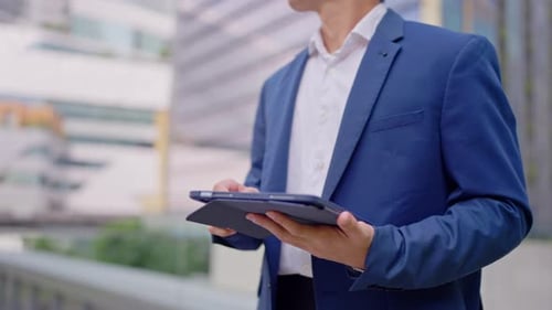 Close up of businessman using digital tablet while standing in the city.
