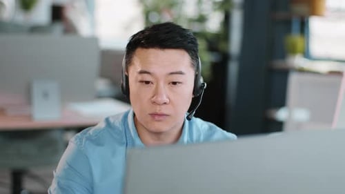 Man in Headset Focused on Work in Modern Office Setting During Daytime Hours