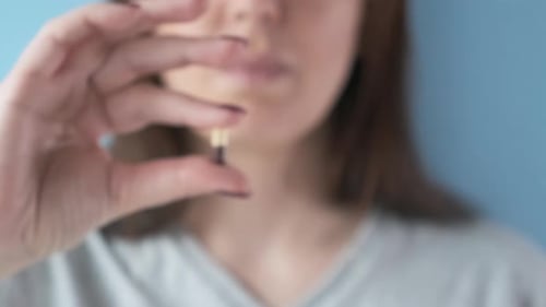 Capsule held between the fingers of a young adult