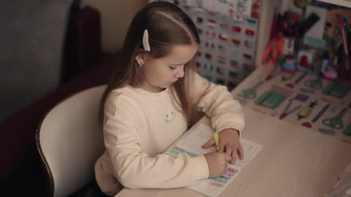 Young Girl Drawing in Notebook at Her Desk