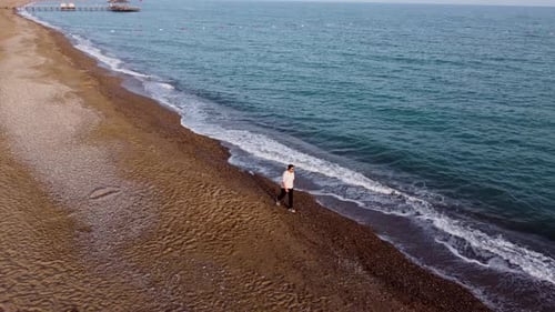 Vista aérea de un joven caminando por la playa 4K
