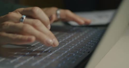 Closeup of Female Hands Typing with Laptop Keyboard While Businesswoman Working at Desk at Night