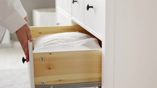 Woman Organizes White Towels in a Dresser Drawer