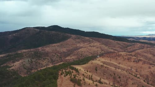 Aerial flyover shot of a temperate mountain range on a cloudy day.