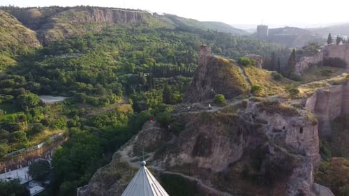 Cinematic drone shot showing hills and revealing beautiful yellow church during sunny day in Tblisi