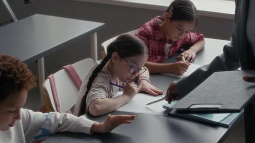 Teacher Assists Students Taking a Test in Classroom