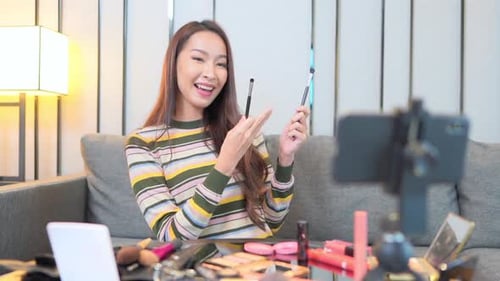 Mujer haciendo un vlog sobre cosméticos con un teléfono inteligente. En el interior, Slomo
.