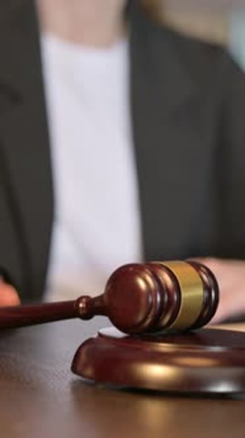 Primer plano del juez golpeando un mazo para anunciar la sentencia, vídeo vertical