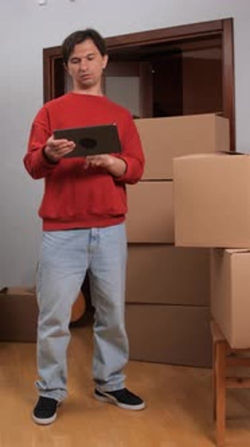 Young Adult Man Using Tablet Near Moving Boxes