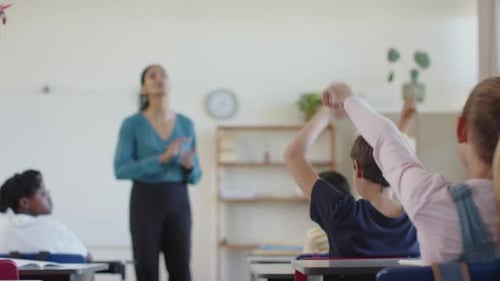 In school, teacher engaging with students sitting at desks in classroom