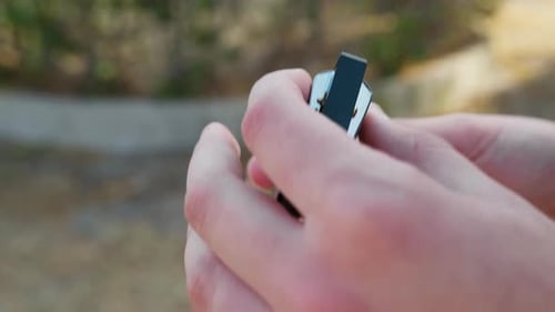 Hands Holding and Opening Harmonica Outdoors