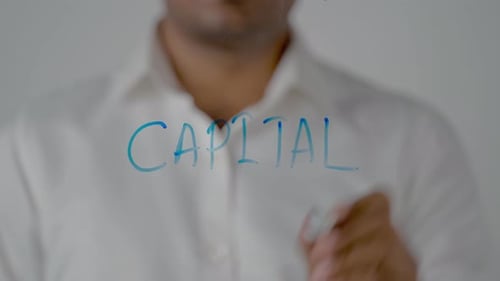 Man Writing Capital on Transparent Glass Screen