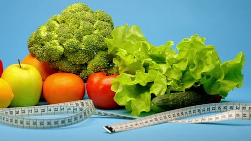 Spraying Fresh Vegetables Wrapped in Measuring Tape and Glass of Green Smoothie