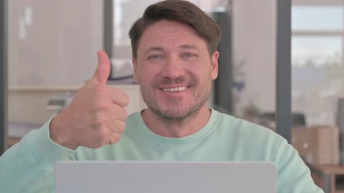 Close up of Thumbs Up by Man Working on Laptop