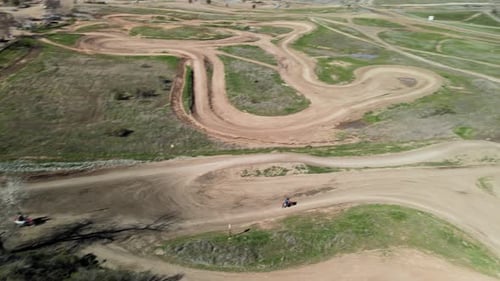 Panning drone footage showing following 2 Motocross riders taking a smooth line around a winding rac