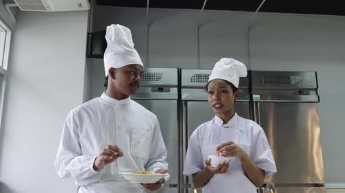 Two African American chefs discussing recipes while walking