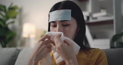 Une jeune femme asiatique malade dans une couverture chaude frissonne de froid avec du gel rafraîchissant