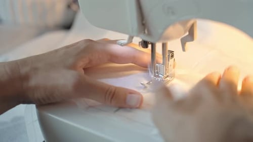 Close Up of Female Hands Using Sewing Machine to Sew Fabric