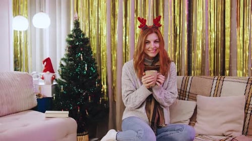 Woman Smiling with Christmas Reindeer Antlers and Coffee