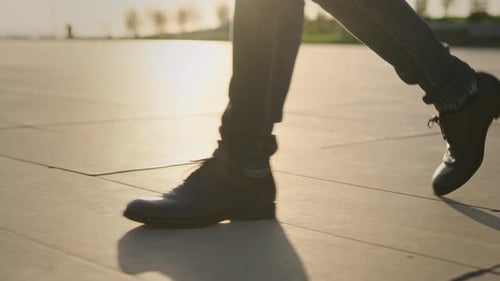 Ein nicht wiederzuerkennender Mann in klassischen Schuhen und Jeans geht über den Platz, Nahaufnahme laufender Füße