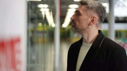 Man Observing Storefront Display with Reflection in Glass at Shopping Mall