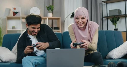 Couple Playing Video Game at Home on Laptop