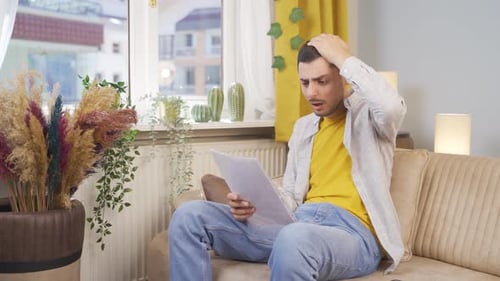 Worried Young Adult Reviews Documents in Home