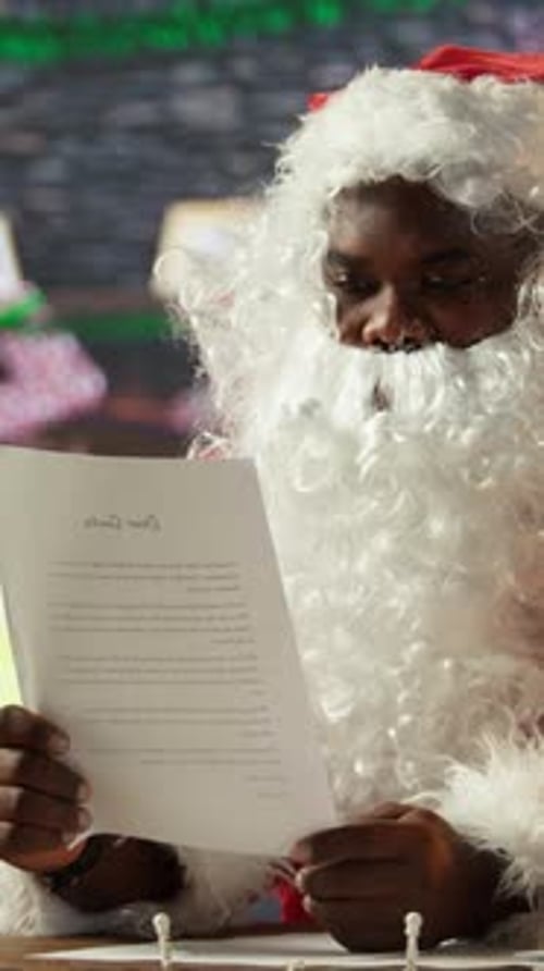 Vertical Video Santa Claus Reads a Christmas Letter By the Fireplace in His Workshop