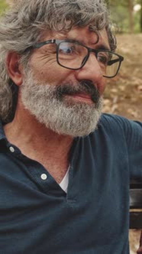Close-up of smiling elderly man relaxing on park bench