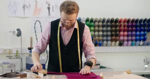 Male Fashion Designer Working on Fabric at Table