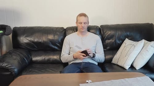 Mann sitzt auf dem Sofa und zeigt leeres Portemonnaie, traurig, weil er kein Geld hat 60 Bilder pro Sekunde