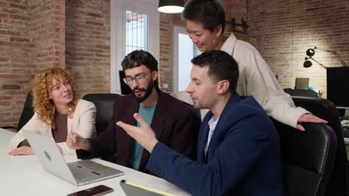 Team Collaboration Around Laptop in Modern Office