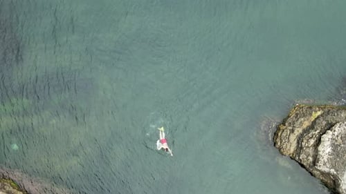 Overhead Shot of Swimmer off Rocky Coastline