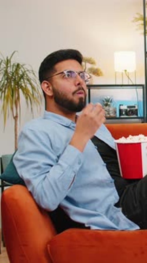 Man Relaxing at Home Eating Popcorn on Couch